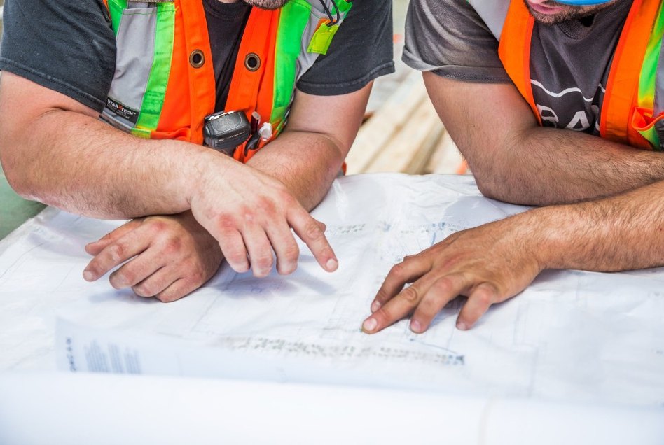 Two tradesmen in hi-vis going over plans together on site